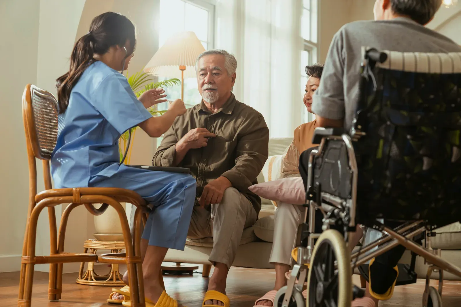 A caregiver talking with an older man in a sunlit room